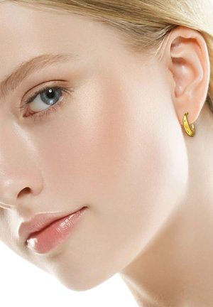 Boucle d'oreille en or avec une finition lisse et polie. Petit design incurvé qui met en valeur l'oreille, complétant un teint clair.