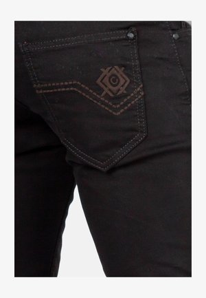 Zwarte denim jeans met een achterzak met een reliëf diamanten patroon en contrasterende stiksels. Smooth textuur met metalen accenten.