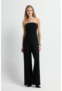 Mono negro sin tirantes con un torso ajustado y pantalones de pierna ancha. Confeccionado en una tela suave, presenta una silueta limpia y costuras mínimas.