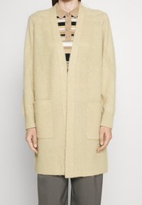 Cardigan lungo aperto in morbido tessuto a maglia beige. Presenta dettagli a coste, due tasche frontali e maniche morbide per il massimo comfort.