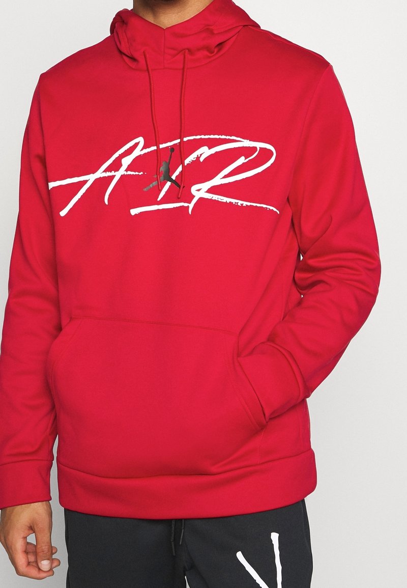 Sweat à capuche rouge en tissu doux, avec un grand imprimé blanc "AIR" et un logo Jordan. Comprend une poche avant et une capuche avec cordon de serrage réglable.