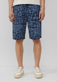 Navy korte broek met een blauw bloemmotief, voorzien van een relaxte pasvorm en een elastische tailleband. Gecombineerd met lichtgekleurde sneakers.