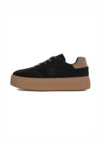 Sneaker in suede nera con suola piatta in gomma beige. Presenta lacci neri e un logo circolare sul lato esterno.