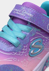 Κοντινή λήψη ενός παιδικού αθλητικού παπουτσιού Skechers σε μωβ και ροζ χρώμα, με μπλε κορδόνια, λαμπερό λουράκι με την επιγραφή "Mermaid Dreams" και διακοσμητικά σχέδια με αστέρια και λέπια.