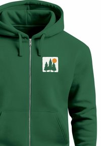 Green zip-up hoodie featuring a white square graphic with two tree silhouettes and a stylized orange sun. Smooth cotton blend material.