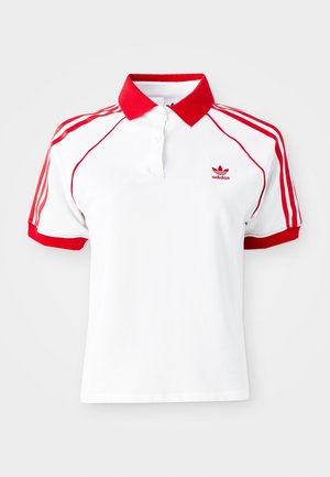 Valge polo särk punase krae ja punaste kolme triibuga aktsentidega õlgadel. Omab nööbiplokki ja väikest punast logo rinnal.