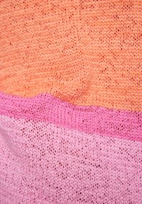 Strickstoff mit abwechselnden Abschnitten in Pfirsich- und Rosatönen. Mit einer lockeren Webart strukturiert, die ein weiches Erscheinungsbild und einen sanften Fall offenbart.