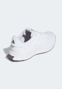 White athletic shoe with a textured mesh upper, three signature stripes, padded collar, and a black rubber outsole with accent detailing.