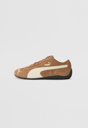 Sneaker bassa in suede marrone con accenti crema, superficie texture, suola in gomma nera e logo ricamato sul lato e sulla linguetta.