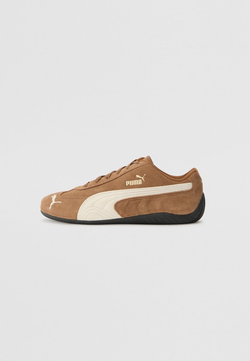 Braune Wildleder-Low-Top-Sneaker mit cremefarbenen Akzenten, strukturierter Oberfläche, schwarzer Gummisohle und gesticktem Logo an der Seite und Zunge.