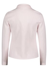 Veste rose pâle avec une coupe structurée, manches longues et col plat. Le tissu est lisse avec des détails de couture minimaux.