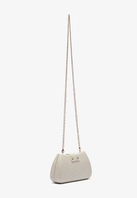 Sac à main en cuir beige clair avec une texture tressée, de forme triangulaire et une bandoulière en chaîne dorée. Comprend un rabat avant et des accents métalliques.