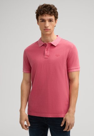 Roze polo t-shirt met korte mouwen, gemaakt van katoen, met een twee-knops sluiting en subtiele logo borduursels op de borst, gecombineerd met donkere spijkerbroeken.