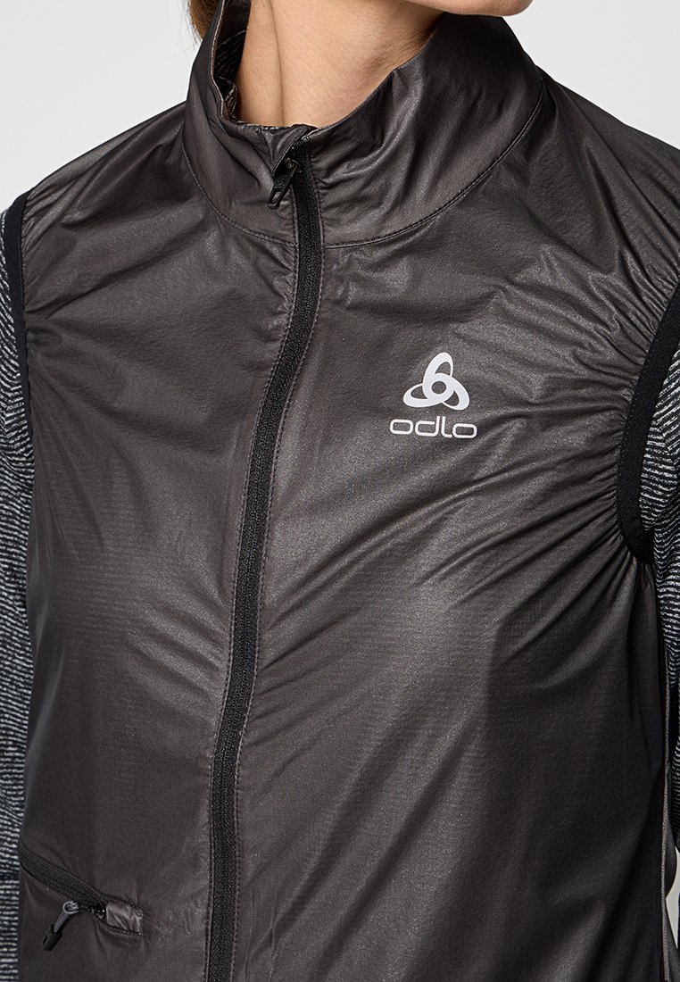 Schwarze leichte ärmellose Jacke mit hohem Kragen, Reißverschluss vorne und Odlo-Logo; ist an den Seiten und Taschen mit strukturiertem grauem Material versehen.