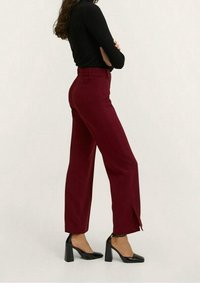 Pantalon bordeaux à jambes larges et taille haute, doté d'une fente à l'avant de l'ourlet. Associé à des chaussures à talons hauts noires brillantes.