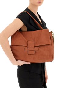 Borsa a tracolla in suede marrone con chiusura a patta e un dettaglio incrociato in evidenza. Presenta una lunga tracolla regolabile e una superficie liscia.