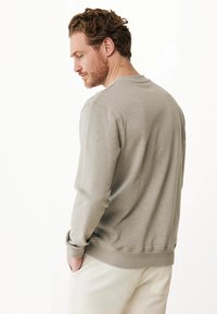 Felpa a maniche lunghe grigia chiara con colletto a girocollo a coste e polsini, caratterizzata da una texture liscia e un design minimalista.