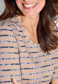 Beige gestreiftes Oberteil mit variierenden blauen Streifen und strukturierter Oberfläche. Rundhals und kurze Ärmel, mit einer lockeren Passform.