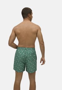 Bañador verde con un patrón náutico de veleros blancos, con cintura elástica y corte relajado. Fabricado con material ligero y transpirable.