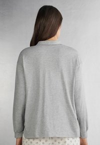 Grijze lange mouwen-shirt met een kraag, gemaakt van zachte stof. Heeft een relaxte pasvorm, manchet aan de polsen en een ronde zoom aan de achterkant.