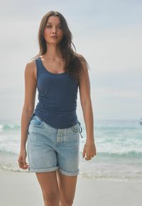 Tumedat sinine top koos külgedel voltide detailidega, sobitatud kergete helesiniste denim lühikesed püksid, millel on rullitud äär. Pehme kangas, lõdvestunud lõige.