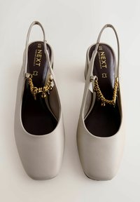 Chaussures beige à bride arrière avec bouts carrés et embellissements en chaîne dorée, marquées "NEXT Forever Comfort", taille 40, photographiées de dessus.