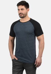 Cotton blend T-shirt with a dark blue body and black raglan sleeves. Round neckline, short sleeves, and minimal stitching details.