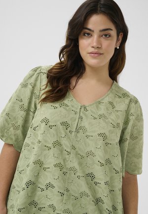 Hellgrüne Bluse mit floraler Stickerei, kurzen Puffärmeln und Knopfleiste vorne. Weiche Textur mit filigranen Ausschnittmustern.