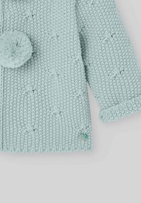 Cardigan tricoté bleu clair avec un motif texturé, doté d'une fermeture à pompon rond et d'une petite étiquette de marque.