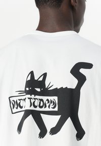 White cotton t-shirt featuring a black graphic of a cat holding a sign that says "NOT TODAY" in bold, stylized font.