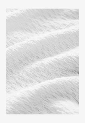 Witte textuurstof met een golvend patroon, die een zachte, lichte materiaal laat zien. Plissee's creëren diepte en subtiele variaties in het oppervlak.