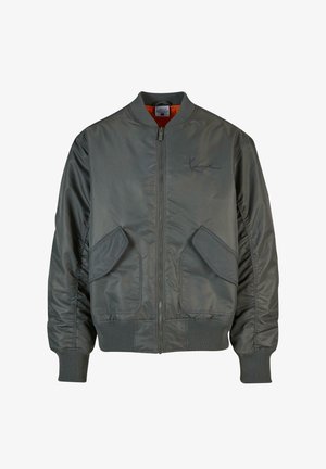 Sivi bomberski jakna s rebrastim manžetama i rubom. Ima dva velika prednja džepa i glatku teksturu. Obložena je narančastom tkaninom.