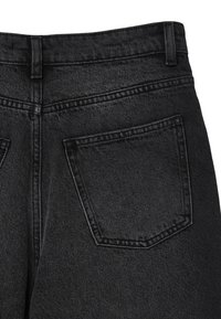Jean noir en denim avec une taille haute, des coutures visibles et une poche arrière unique de forme rectangulaire. Texture lisse.