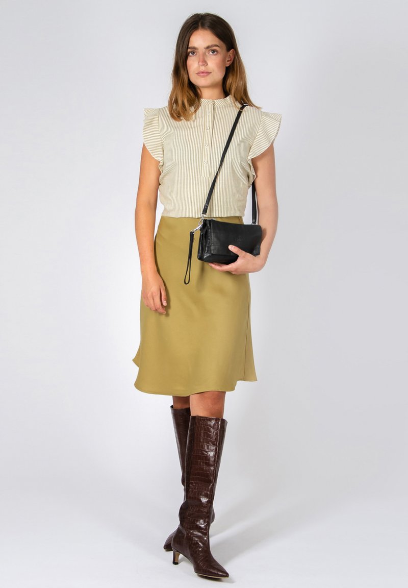 Blusa a righe con maniche a volant, gonna verde oliva e stivali marroni fino al ginocchio. Borsa a tracolla nera con cinturino. Tessuto morbido e design elegante.