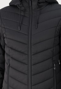 Czarna puchowa kurtka z zamkiem z przodu, kapturem i wzorem w zygzak. Posiada dwie boczne kieszenie, gładką teksturę i regulowane sznurki.