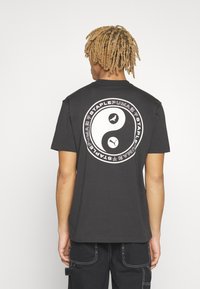 Puma PUMA STAPLE TEE - Apdrukāts T-krekls - puma black
