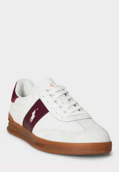 Witte sneaker met bordeaux accenten en een textuurafwerking. Voorzien van een vetersluiting, rubberen zool en geborduurde logodetails.