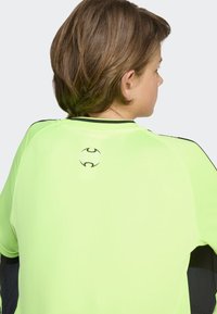 Lys neon grønn treningsskjorte med horisontal ribbestruktur, svarte detaljer på ermene og en logo på baksiden nær nakkekanten.