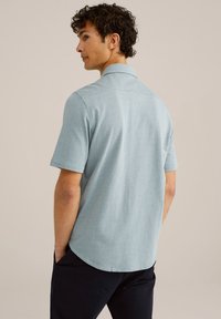 Šviesiai mėlyna marškinėlių trumpomis rankovėmis, su tekstūruotu raštu, apykakle ir diskreti šonu siūle gale. Kasdienis siluetas su suapvalintu kraštu.