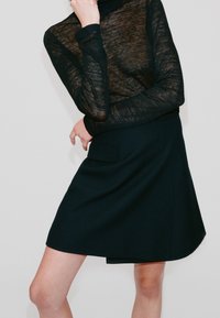 Schwarzer, transparenter Rollkragenpullover kombiniert mit einem schwarzen, knielangen Rock mit Seitentasche; beide haben glatte Texturen und eine maßgeschneiderte Passform.