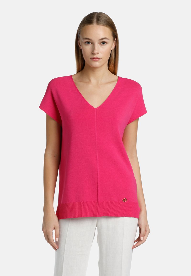 Fuchsia knitted top with a V-neck, short sleeves, and a slightly relaxed fit. Features a ribbed hem and a small emblem on the lower side.