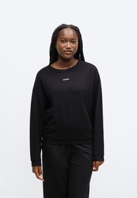 Musta collegepaita pyöreällä pääntiellä ja pitkillä hihoilla, jossa valkoinen "HUGO"-logo, valmistettu pehmeästä, sileästä kankaasta.