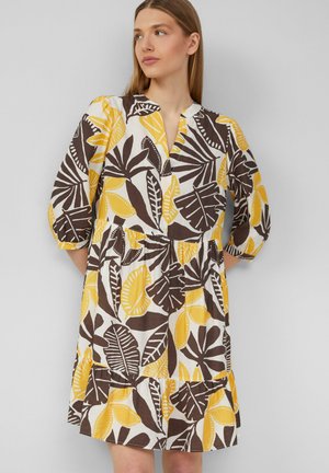 Vestito a maniche corte in bianco con motivi di foglie gialle e marroni. Presenta una scollatura a V, una vita arricciata e un design a gonne sovrapposte.