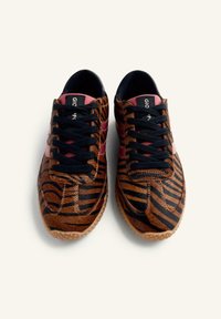 Sneakers a strisce marroni e nere con una parte superiore testurizzata, dotati di lacci neri, accenti rosa e suola in gomma. Il design è sportivo e casual.