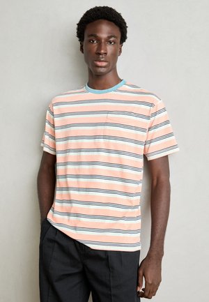 Gestreiftes T-Shirt in zartem Orange, Blau und Weiß. Runder Halsausschnitt, kurze Ärmel und kleine Brusttasche.