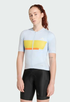 Světle modrý cyklistický dres s krátkými rukávy, žluto-oranžovým geometrickým vzorem, s předním zipem a černé cyklistické šortky.