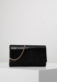 Pochette noire ornée de sequins avec rabat pliant et chaîne dorée. Corps à texture lisse, forme rectangulaire, silhouette élancée.