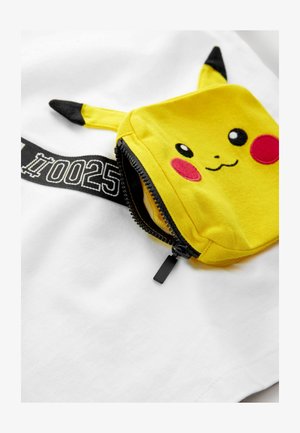 Balta T-kreklā ir dzeltena Pikachu kabata ar melnajām akcentām, izšūti sejas sīkumi un ar rāvējslēdzēju. Redzama melna drukāta birka.