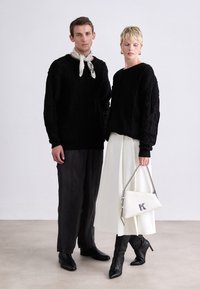 Black knitted sweaters with cable patterns, gray wide-leg trousers, and a white skirt. Black pointed boots and a white handbag with a logo.