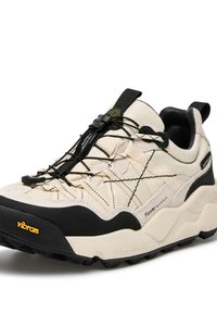 Scarpa da trekking beige chiaro e nera con materiali in rete e gomma, caratterizzata da una suola testurizzata, lacci elastici e marchio Vibram.